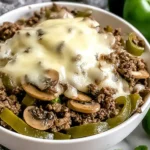 Philly Cheesesteak Bowls topped with melted cheese, sautéed mushrooms, and green bell peppers in a white bowl.