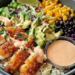 Crispy Fish Taco Bowls with golden breaded fish, avocado, corn, black beans, slaw, and chipotle lime crema over rice.