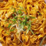 Close-up of creamy Gochujang Chicken Alfredo pasta with shredded chicken, scallions, and Parmesan in a bowl.