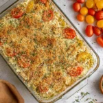 White Bean and Pesto Bake topped with golden panko crumbs, Parmesan, and cherry tomatoes in a glass casserole dish.