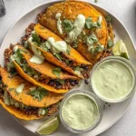 Plate of Crispy Baked Ground Turkey Tacos with avocado sauce, black beans, and fresh cilantro.