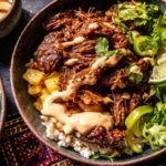 Crockpot Chipotle Pineapple Pot Roast Bowls with shredded beef, pineapple, fresh cilantro, lime, and creamy chipotle sauce over rice.
