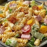 Bowl of creamy Club Sandwich Pasta Salad with rotini, ham, turkey, bacon, lettuce, tomato, and cheddar tossed in ranch dressing.