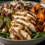 Maple Dijon Chicken served with roasted sweet potatoes, Brussels sprouts, pecans, and rice in a hearty grain bowl.