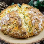 Cheddar and Herb Soda Bread with a rustic golden crust, studded with sharp cheddar and fresh herbs, ready to be sliced and enjoyed.
