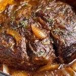 Slow-braised French Onion Pot Roast with caramelized onions and rich gravy in a Dutch oven, showcasing tender beef and golden onion sauce.