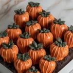 Close-up of Pumpkin Patch Strawberries decorated with orange chocolate to look like tiny pumpkins, arranged on a cookie crumb “dirt” base.