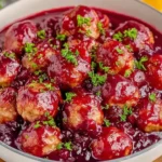 Delicious Quick Cranberry Meatballs coated in tangy cranberry sauce, garnished with parsley for a festive holiday dish.