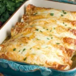 Cheesy Thanksgiving Enchiladas baked in a casserole dish topped with golden melted cheese and fresh herbs