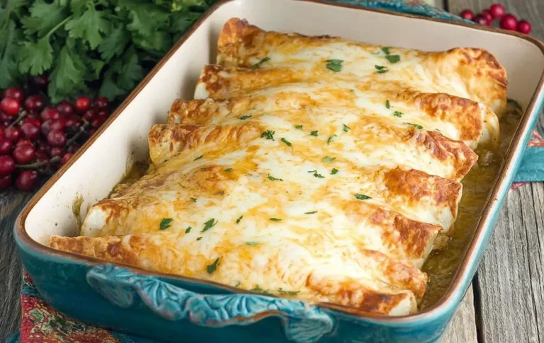 Cheesy Thanksgiving Enchiladas baked in a casserole dish topped with golden melted cheese and fresh herbs
