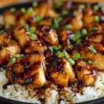 Close-up of Honey BBQ Chicken Rice topped with sweet smoky sauce and fresh green onions served over fluffy white rice in a skillet.