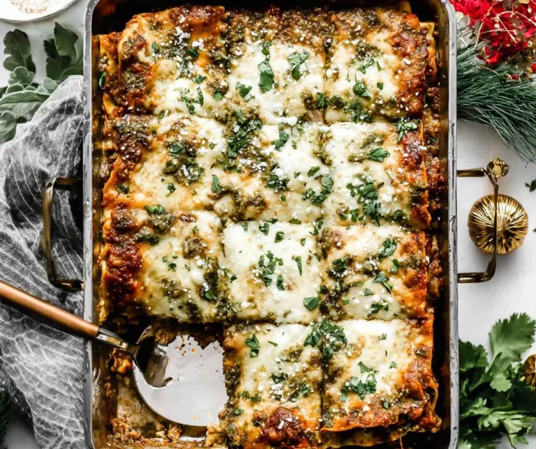 Golden-baked Christmas Eve Lasagna topped with melted cheese, pesto, and fresh herbs in a festive holiday setting.