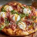 Prosciutto and Honey Burrata Pizza topped with creamy burrata, salty prosciutto, arugula, and golden honey drizzle on a crisp, wood-fired crust.