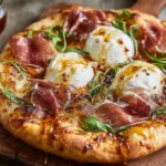 Close-up of Prosciutto and Honey Burrata Pizza topped with creamy burrata, prosciutto, arugula, and a drizzle of honey on a golden crust.