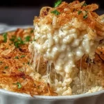 Creamy French Onion Chicken Rice Bake topped with crispy fried onions and melted cheese in a white casserole dish.