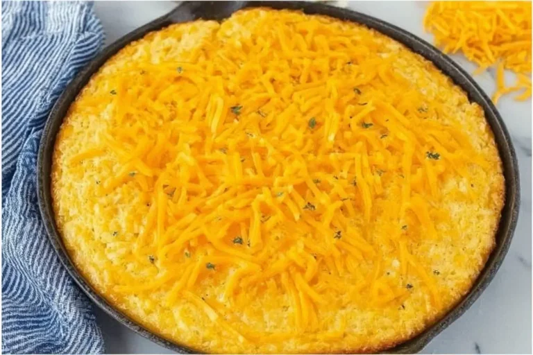 Golden-baked Paula Deen’s Corn Casserole topped with melted cheddar cheese in a cast iron skillet.