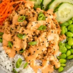 Ground Turkey Rice Bowls topped with creamy bang bang sauce, fresh vegetables, and white rice in a colorful, vibrant bowl.