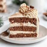 Slice of Christmas Spice Cake with Eggnog Buttercream showing layered spices, creamy frosting, and cinnamon garnish on a plate.