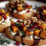 Fall Bruschetta topped with roasted butternut squash, goat cheese, pomegranate seeds, and balsamic glaze on toasted ciabatta bread.