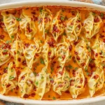 Trader Joe’s Dumpling Bake in red curry coconut sauce topped with chili crisp and cilantro in a white baking dish.