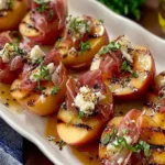 Grilled Apples with Prosciutto and Honey topped with creamy goat cheese, fresh herbs, and a golden honey drizzle on a white serving platter.