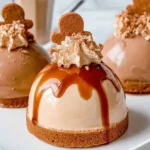 Close-up of Gingerbread Latte Mousse Domes topped with whipped cream and gingerbread cookies, featuring glossy glaze and a spiced cookie base