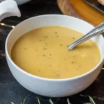 Perfect Turkey Gravy in a white bowl with pepper and herbs