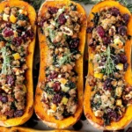 Apple Sausage Stuffed Butternut Squash baked with savory sausage, kale, apples, pecans, and cranberries, topped with fresh rosemary
