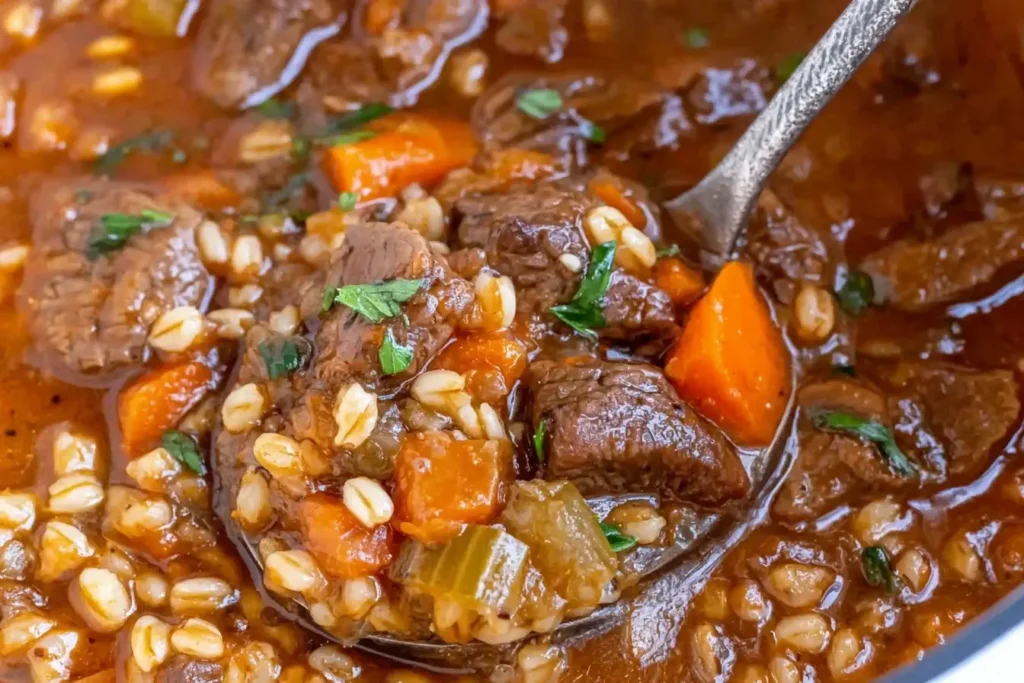 Close-up of rich Beef Barley Soup with tender beef, carrots, celery, and barley on a spoon.