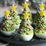 Festive Deviled Egg Christmas Trees decorated with green whipped filling, red pepper “ornaments,” and yellow bell pepper stars on a holiday platter.