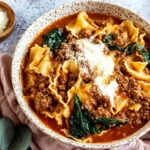 One Pot Lasagna Soup served in a rustic bowl with lasagna noodles, beef, spinach, and creamy ricotta on top.