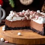 Rich and creamy Hot Chocolate Cheesecake with Oreo crust, topped with whipped cream, mini marshmallows, chocolate shavings, and crushed candy canes.