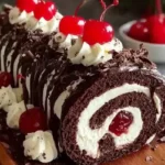 Elegant Black Forest Cake Roll with chocolate sponge, whipped cream filling, cherry center, chocolate drizzle, and shaved chocolate on a wooden tray.