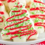 Homemade Christmas Tree Cakes coated in white chocolate with red drizzle and green sprinkles