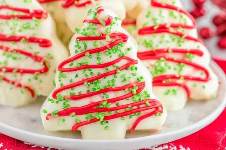 Homemade Christmas Tree Cakes coated in white chocolate with red drizzle and green sprinkles