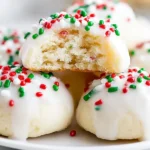 Soft Italian Christmas Cookies topped with white glaze and festive red, green, and white sprinkles, with one cookie showing a tender, fluffy inside.