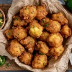 Crispy golden Jalapeno Corn Nuggets served on parchment paper with fresh jalapeños and sweet corn on the side.