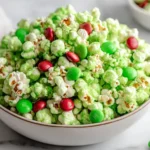 Grinch Popcorn Mix in a white bowl with green candy-coated popcorn, red and green M&Ms, and a festive holiday look perfect for Christmas parties.