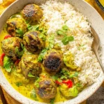 Jerk Meatballs In Coconut Curry Sauce served over fluffy basmati rice, topped with fresh cilantro and sliced peppers in a creamy golden curry.