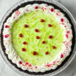 No Bake Grinch Pie topped with green sugar and red heart candies in an Oreo crust
