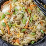Egg Roll in a Bowl with ground turkey, sautéed cabbage, shredded carrots, green onions, and sesame seeds in a black bowl.
