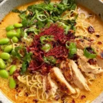 Creamy Marry Me Chicken Ramen in a bowl with sliced seared chicken, ramen noodles, creamy tomato-Parmesan broth, edamame, scallions, and chili oil