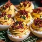 Christmas Deviled Eggs topped with crispy bacon, paprika, and fresh herbs, served on a festive holiday platter