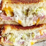 Viral Grinder Grilled Cheese Sandwich stacked and sliced, with melty cheddar and mozzarella, deli ham, crunchy grinder salad, and golden toasted bread.