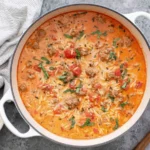 Italian Sausage Orzo Soup simmering in a white Dutch oven with creamy broth, tender orzo, sausage crumbles, tomatoes, and fresh herbs