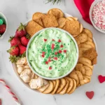 Grinch Dip served on a festive holiday platter with crackers, strawberries, marshmallows, and heart sprinkles for a Christmas dessert board