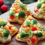 Christmas Tree Cold Veggie Pizza made with crescent dough, hummus, and colorful fresh vegetables, shaped like festive holiday trees.