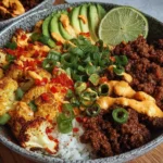 Crispy Chile Ground Beef and Cauliflower protein bowl with browned ground beef, roasted cauliflower, avocado slices, scallions, lime, and creamy spicy drizzle.
