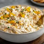 Creamy Banana Pepper Chicken Dip served warm in a bowl, topped with sliced banana peppers and herbs, surrounded by crackers for dipping