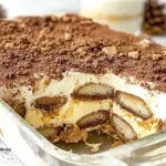 Gingerbread Tiramisu layered with mascarpone cream, gingerbread cookies, and cocoa topping in a glass dish with a slice removed.
